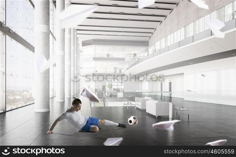 Football game player. Football player in modern office interior kicking ball