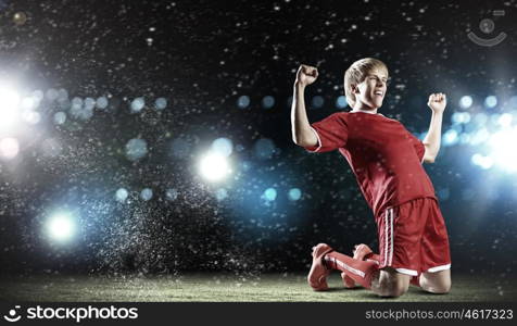 Football goal. Football player standing on knees and screaming with joy