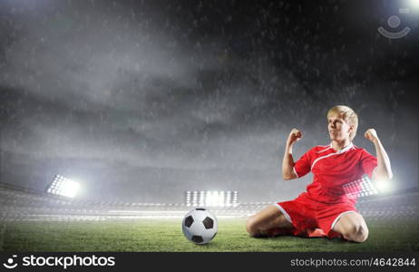 Football goal. Football player standing on knees and screaming with joy