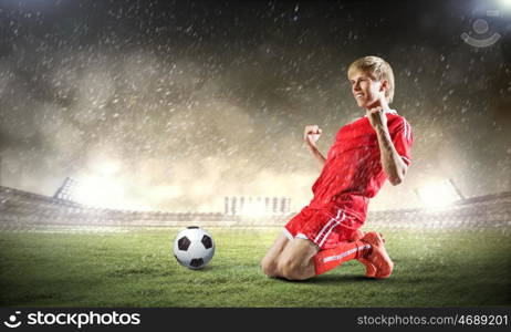 Football goal. Football player standing on knees and screaming with joy