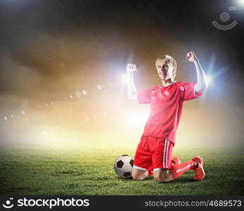 Football goal. Football player standing on knees and screaming with joy