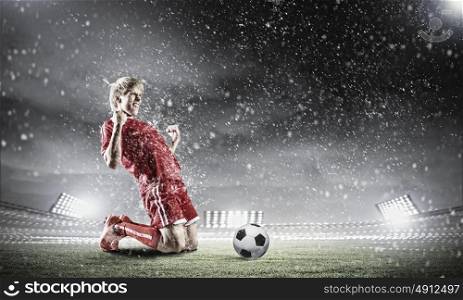 Football goal. Football player standing on knees and screaming with joy