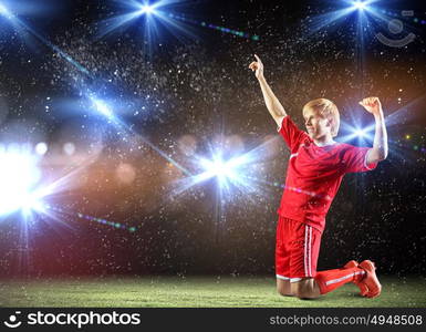 Football goal. Football player standing on knees and screaming with joy