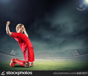 Football goal. Football player standing on knees and screaming with joy