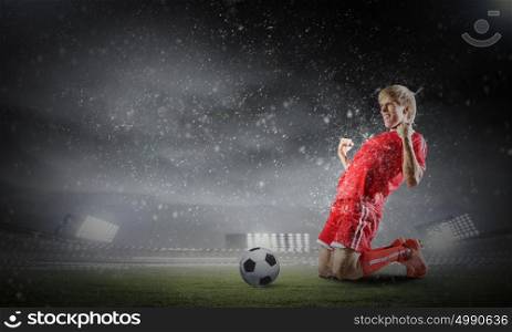 Football goal. Football player standing on knees and screaming with joy