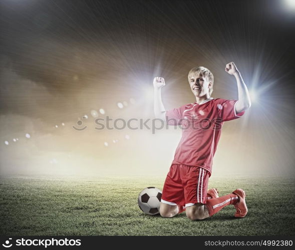 Football goal. Football player standing on knees and screaming with joy