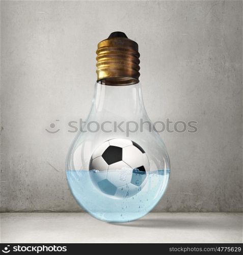 Football idea. Glass lightbulb with football inside floating in water