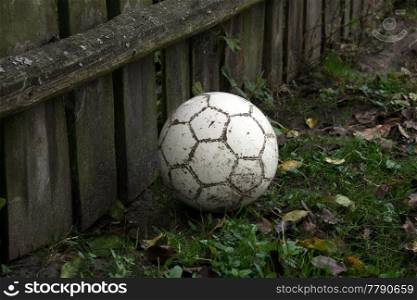Football is a ball on the grass near an old wooden fence