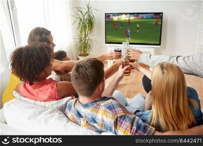 football, leisure and people concept - happy friends clinking beer bottles and watching soccer game on tv at home. friends clinking beer and watching soccer game