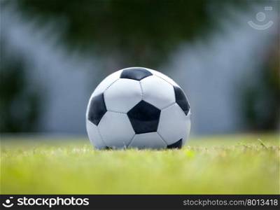 Football on green grass. Close-up shot of a soccer ball on green grass. Defocused background and foreground