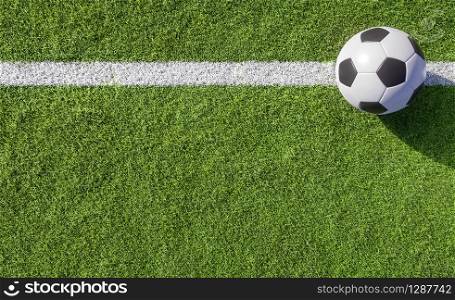 Football or soccer ball lying on a white line on green turf of a sports field placed to the side with copy space viewed from above