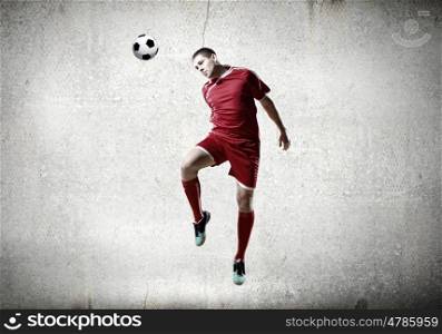 Football player. Football player kicking ball against cement background