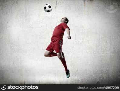 Football player. Football player kicking ball against cement background