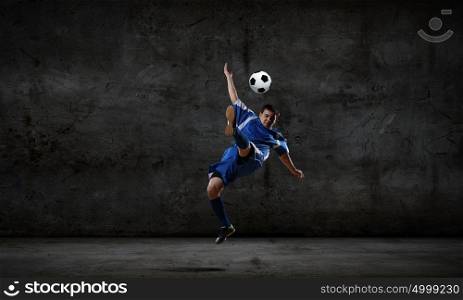 Football player. Football player kicking ball against dark background