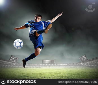 football player in blue shirt striking the ball aloft at the stadium