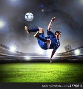 football player striking the ball. football player in blue shirt striking the ball aloft at the stadium