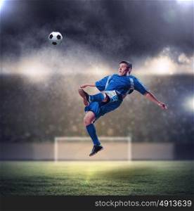 football player striking the ball. football player in blue shirt striking the ball aloft at the stadium