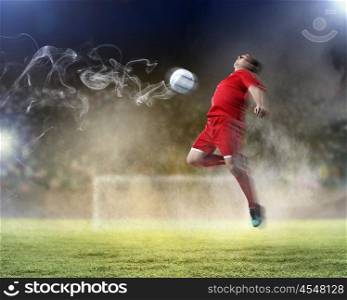 football player striking the ball. football player in red shirt striking the ball at the stadium