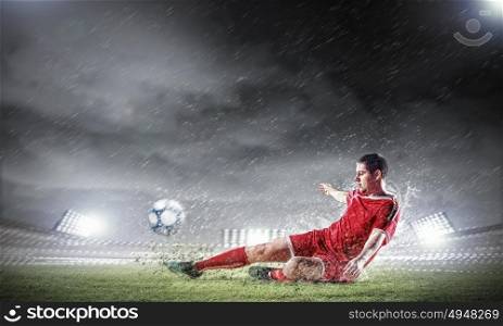 football player striking the ball. football player in red shirt striking the ball at the stadium under rain
