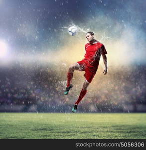 football player striking the ball. football player in red shirt striking the ball at the stadium under rain