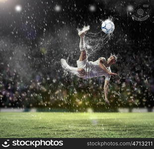 football player striking the ball. football player in white shirt striking the ball at the stadium under the rain