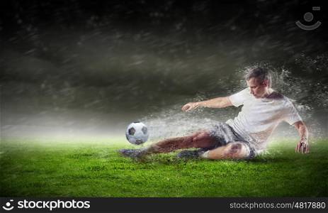 football player striking the ball. football player in white shirt striking the ball at the stadium under the rain