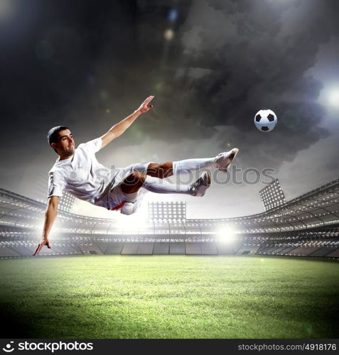 football player striking the ball. football player in white shirt striking the ball at the stadium