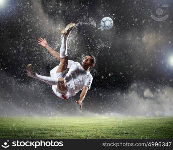 football player striking the ball. football player in white shirt striking the ball at the stadium under rain