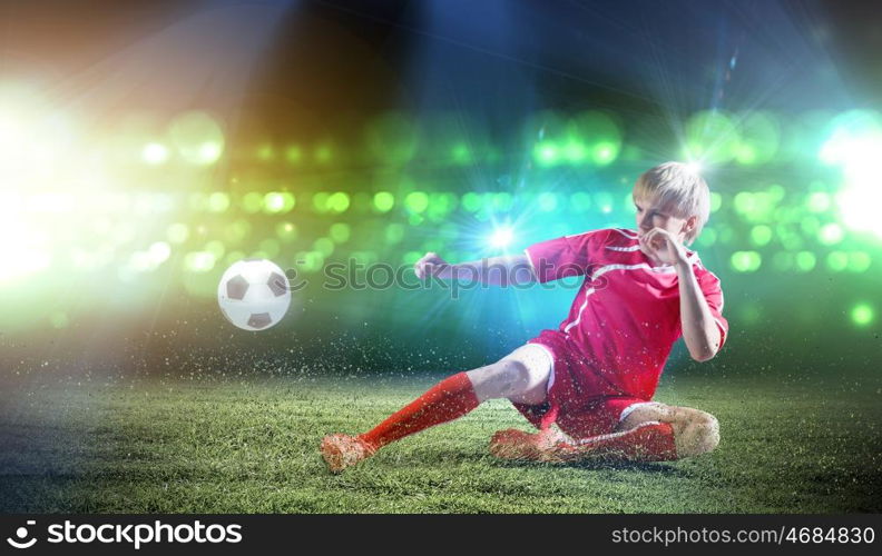 Football player. Young football player on stadium doing slide tackle