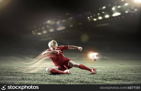 Football player. Young football player on stadium doing slide tackle