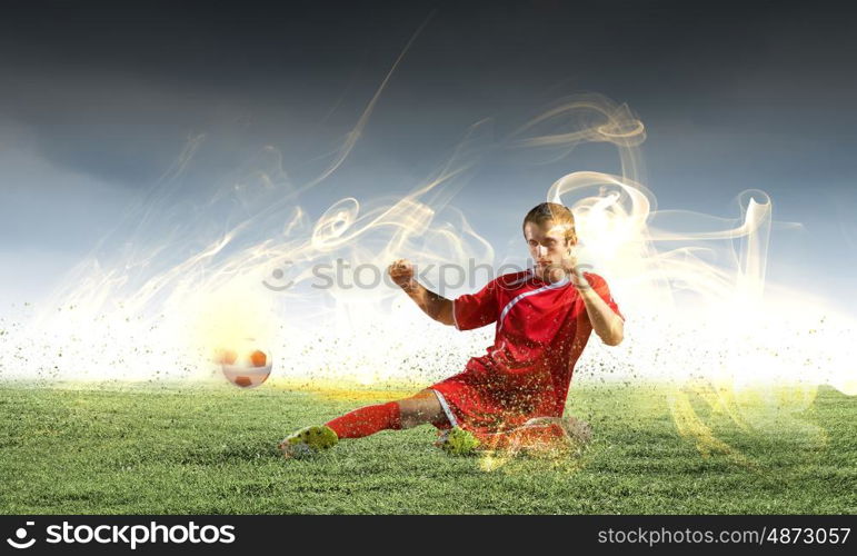 Football player. Young football player on stadium doing slide tackle