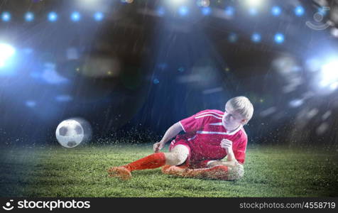 Football player. Young football player on stadium kicking ball