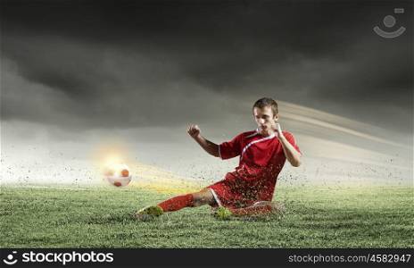 Football player. Young football player on stadium kicking ball