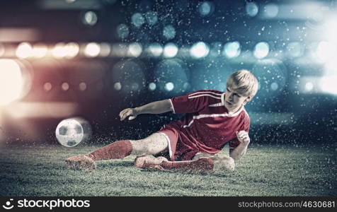 Football player. Young football player on stadium kicking ball