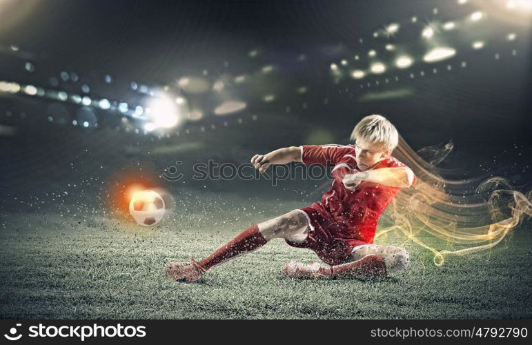 Football player. Young football player on stadium kicking ball