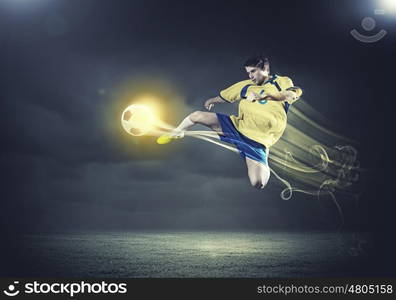 Football player. Young football player on stadium kicking ball