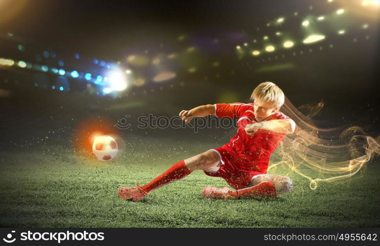 Football player. Young football player on stadium kicking ball