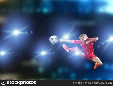 Football player. Young football player on stadium kicking ball