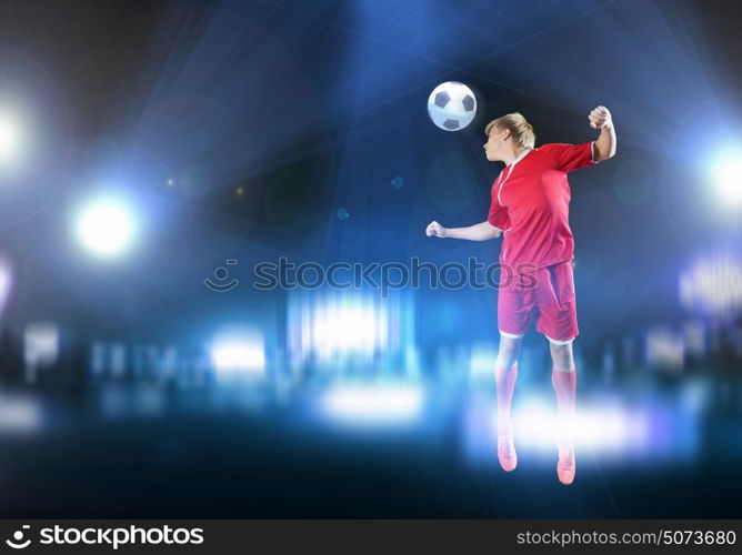 Football player. Young football player on stadium kicking ball