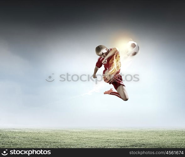 Football player. Young football player on stadium kicking ball in jump