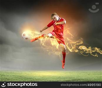 Football player. Young football player on stadium kicking ball in jump