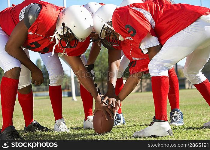 Football Players in Huddle Holding Football