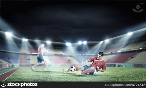 Football players. Two football player fighting for ball at stadium