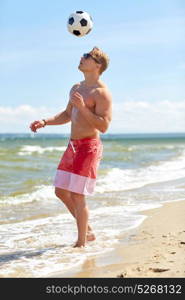 football, sport, fitness and people concept - young man with ball playing soccer on summer beach. young man with ball playing soccer on beach