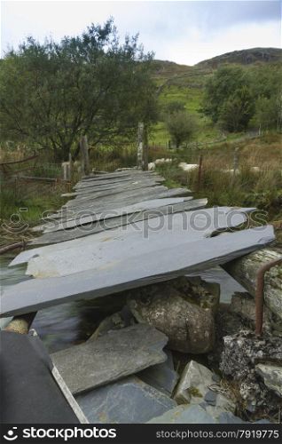 Footbridge over stream Afon Croesor, Gwynedd, Wales, United Kingdom, made from slate slabs, tilted at an alarming angle.