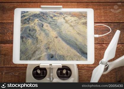 foothills of Rocky Mountains in northern Colorado with trails and paths, reviewing aerial image on a digital tablet mounted on a dron radio controller