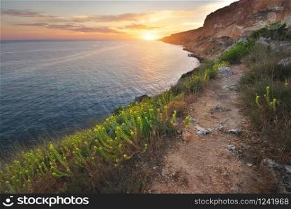 Footpath in mountains above the sea at sunset. Scenic landscape