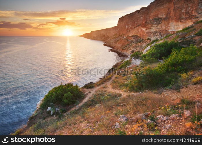 Footpath in mountains above the sea at sunset. Scenic landscape