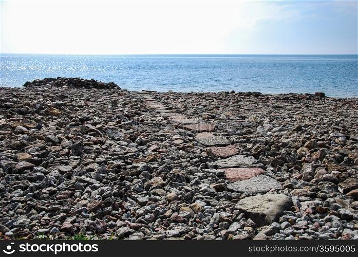 Footpath to the sea at a stony coast.