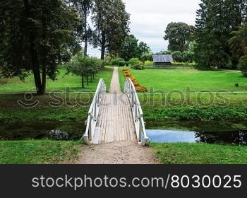 Footpath with white wooden bridge in old park of the village Mikhailovskoye, Pushkinskiye Gory Reserve, Russia